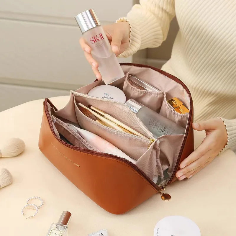 Brown toiletry bag for women, Fancy material and look, Metal zipper, Top view, Handle, Women's' hand using it, Opened toiletry bag, Filled with quality makeup, Bag sitting on table, Lifestyle image, Neutral colors