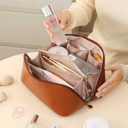 Brown toiletry bag for women, Fancy material and look, Metal zipper, Top view, Handle, Women's' hand using it, Opened toiletry bag, Filled with quality makeup, Bag sitting on table, Lifestyle image, Neutral colors